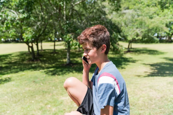 庭で携帯を持つ少年 — ストック写真