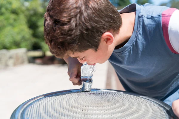 Niño en la fuente de agua disfrutando de una bebida fresca — Foto de Stock