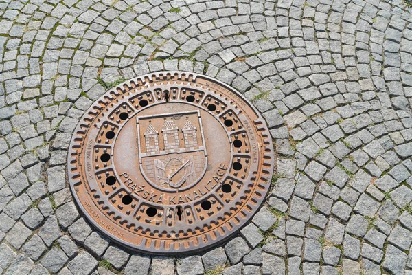 Kanaldeckel in Prager Kopfsteinpflasterstraße. — Stockfoto