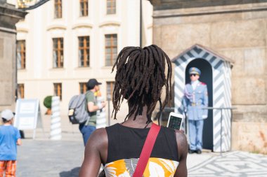 Dreadlocks ve turistler Prag Kalesi çevresinde siyah kadınla bir