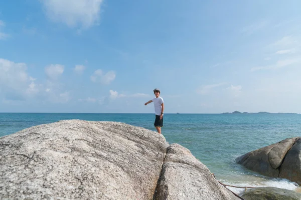 Boy standing on large rock on water's edge on Bang Kao beach Ko — Stock Photo, Image