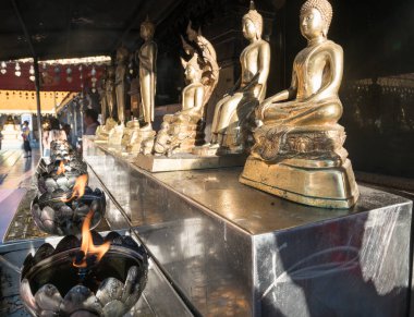 Altın Buda heykelleri altında yanan alevler ile bankta satırı 