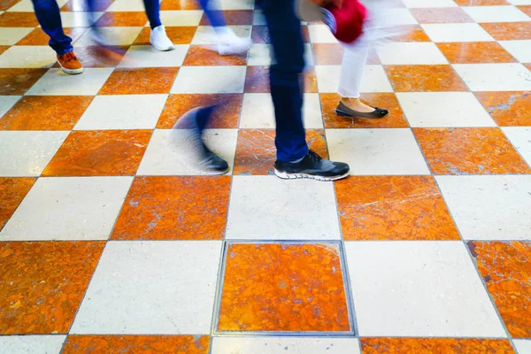 Gambe sfocate e scarpe di gruppo che camminano attraverso piastrelle di marmo f — Foto Stock