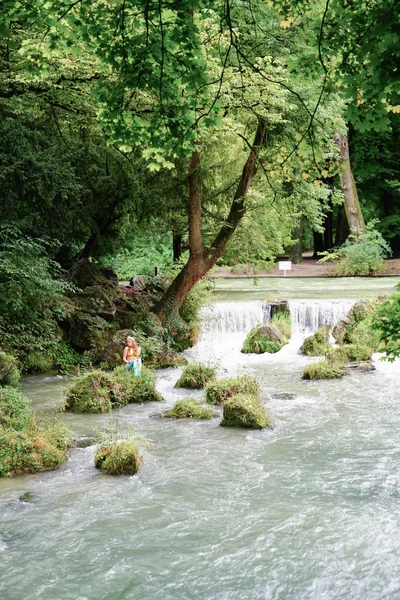 Mulher de terno de sereia senta-se na rocha no rio Eisbach por cachoeira — Fotografia de Stock