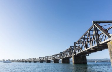 Tauranga harbour with steel railway bridge crossing clipart