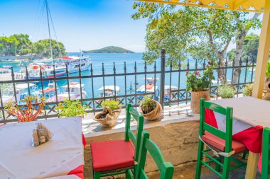 Kırmızı yastıklı yeşil sandalyeler ve balkon kafede masalar. 