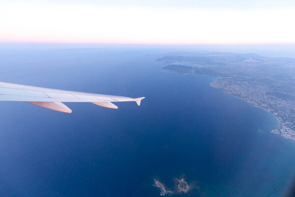 View through plane window of of wing and Greek landscape below a