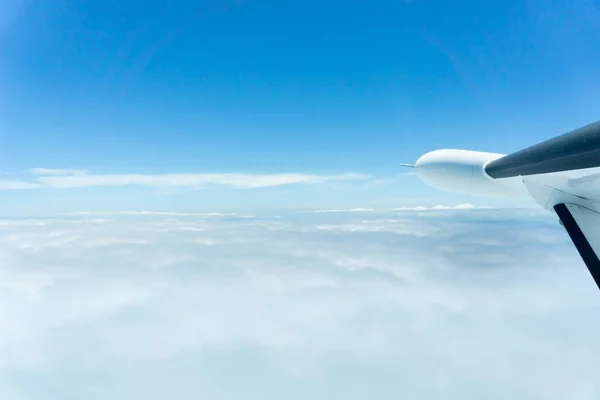 Durch Fenster eines kleinen Flugzeugs, das über Wolken fliegt, — Stockfoto