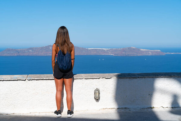 Woman from back standing looking out to sea and islands.