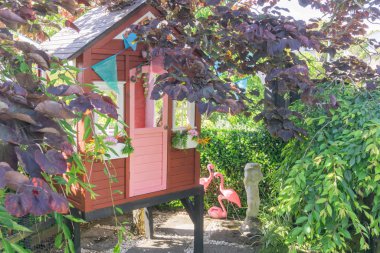 Bahçenin yapraklı alanındaki çocuk oyun evi.