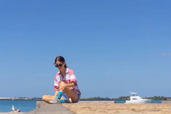 Trendy female teenager sitting on pier on Tauranga waterfront. — Stock Photo, Image