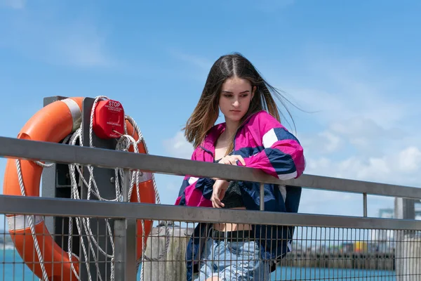 Mulher adolescente atraente fica apoiada no corrimão beira-mar ne — Fotografia de Stock