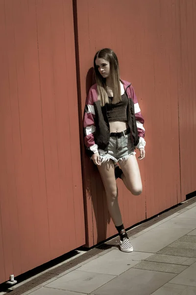Teenager dívka stojící a opírající se o jasně oranžové dveře. — Stock fotografie