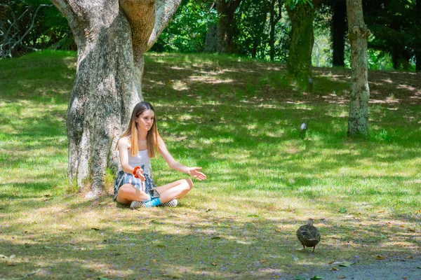 Atractiva adolescente sentada en la base del árbol — Foto de Stock