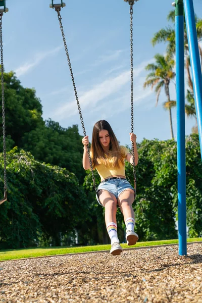 Teenage girl enjoys playing in children's playground.