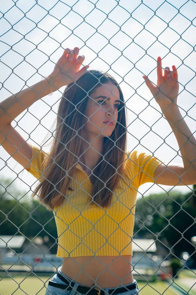 Adolescente de pé com os braços levantados atrás cerca elo cadeia . — Fotografia de Stock
