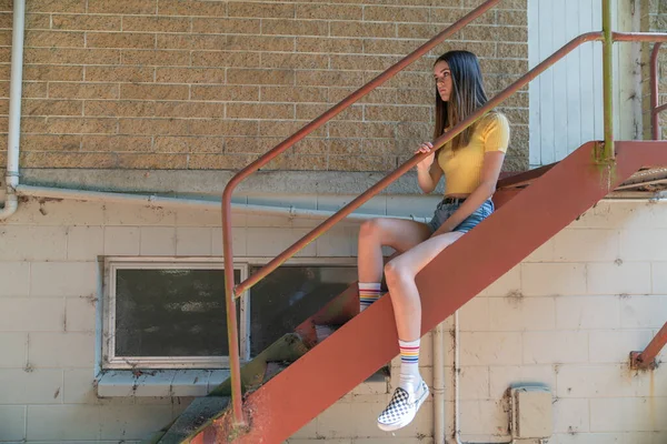 Aantrekkelijk tienermeisje contrasteert met ruwe stalen trap achter b — Stockfoto