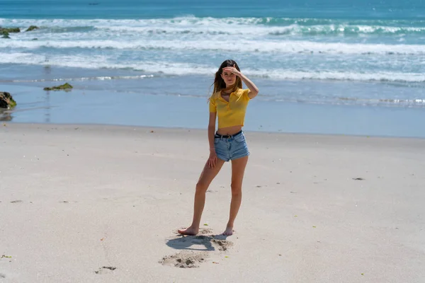 Attraktiv lång flicka står på stranden nonchalant med handen upp shi — Stockfoto