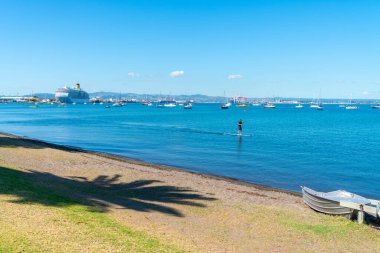 Tauranga Yeni Zelanda - 26 Şubat 2020; Tauranga Limanı 'ndaki yolcu gemisi, Pilot Koyu' nun sonunda Sup kürekleri önden geçerken ve Phoenix Palm Shadow sahilden geçerken yanaştı..