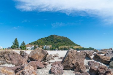 Maunganui Dağı, ana plajın sonunda kayalık ön planda, Tauranga Yeni Zelanda.