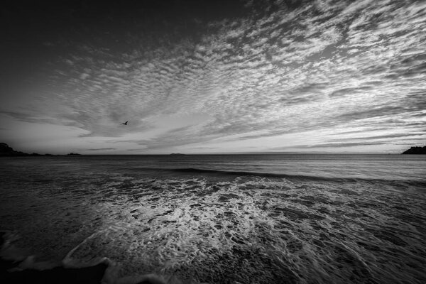 Opposing patterns of clouds in sky and backwash of waves on sand at Mount Maunganui Main Beach, Tauranga New Zealand.