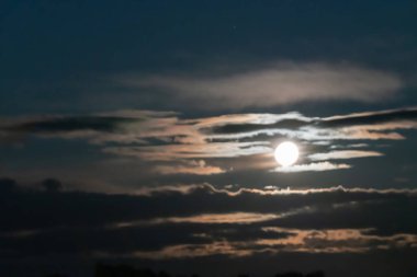 Dolunayın parlaklığı bulut ışığıyla kısmen gizlenmiş..