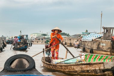Can Tho Vietnam - 14 Ekim 2013; Turuncu elbiseli ve konik şapkalı bir kadın Mekong 'un yüzen teknelerinde yol alıyor.