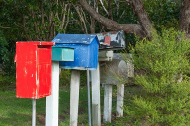 Ağaçlar arasında eski tarz ve renk posta kutularının satırı.