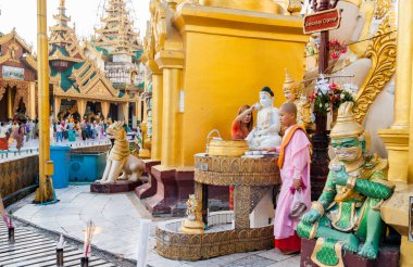 Yangon Myanmar - 8 Kasım 2013; Shwedagon Pagoda 'da ayakta duran rahibe ile Cumartesi Köşesi altın kaplama yapılar ve süslü kuleler.
