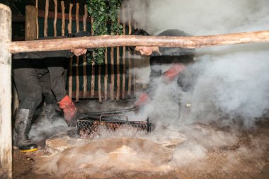 Rotorua Yeni Zelanda - Nisan 2014; Yiyecek olarak duman ve toz sineği geleneksel bir maori ziyafeti ya da Hangi için hazırlanıyor, yeraltı termal aktivitesi veya çukurun tabanındaki ısıtılmış taşlar tarafından ısıtılarak..