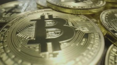 Piles of Gold Bit Coins. Wide macro lens extreme close up (ECU) moving over piles of golden bitcoin medallions with a capital B () symbol and circuit design.