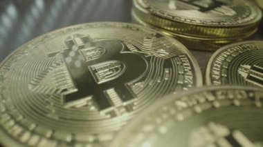 Bit Coin Loose Change. Wide macro lens extreme close up (ECU) moving over scattered golden bitcoin medallions with a capital B () symbol and circuit design.
