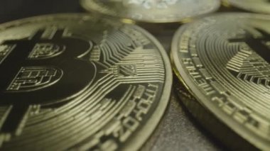 Row of Bit Coins, Horizontal. Wide macro lens extreme close up (ECU) moving across a horizontal row of golden bitcoin medallions with a capital B () symbol and circuit design.
