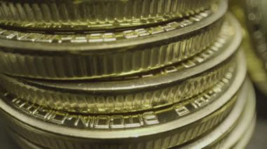 Stacks of Bit Coins. Wide macro lens extreme close up (ECU) moving past a bunch of stacked golden bitcoin medallions with a capital B () symbol and circuit design.