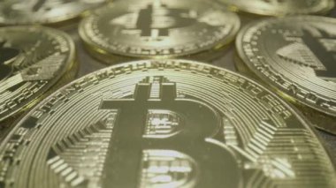 Row of Bit Coins, Vertical. Wide macro lens extreme close up (ECU) moving across a vertical row of golden bitcoin medallions with a capital B () symbol and circuit design.