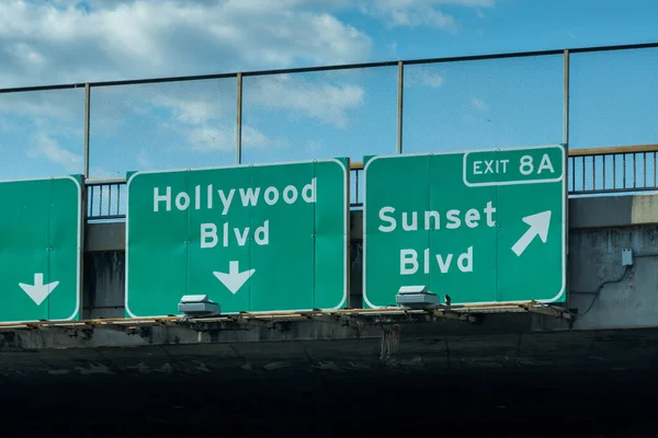 Signs for the Hollywood Blvd and Sunset Blvd exits along the northbound 101 freeway in Los Angeles, California.