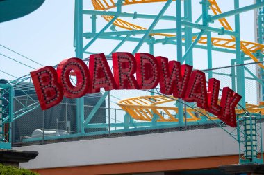 Büyük bir Boardwalk tabelası. Kemerinde ampuller asılı büyük kırmızı blok harfleri..