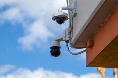 Security Cameras. Two domed security cameras mounted off the corner of a building. clipart