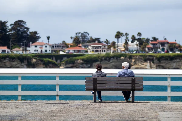 Quiet View. Two people sit and enjoy the ocean view from a park bench on the wharfe in Santa Cruz, California.