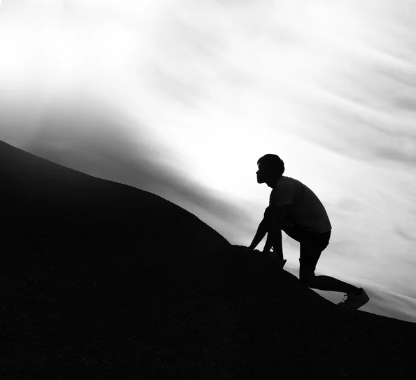 Preto e branco, silhueta de homem escalando montanha com dramat — Fotografia de Stock