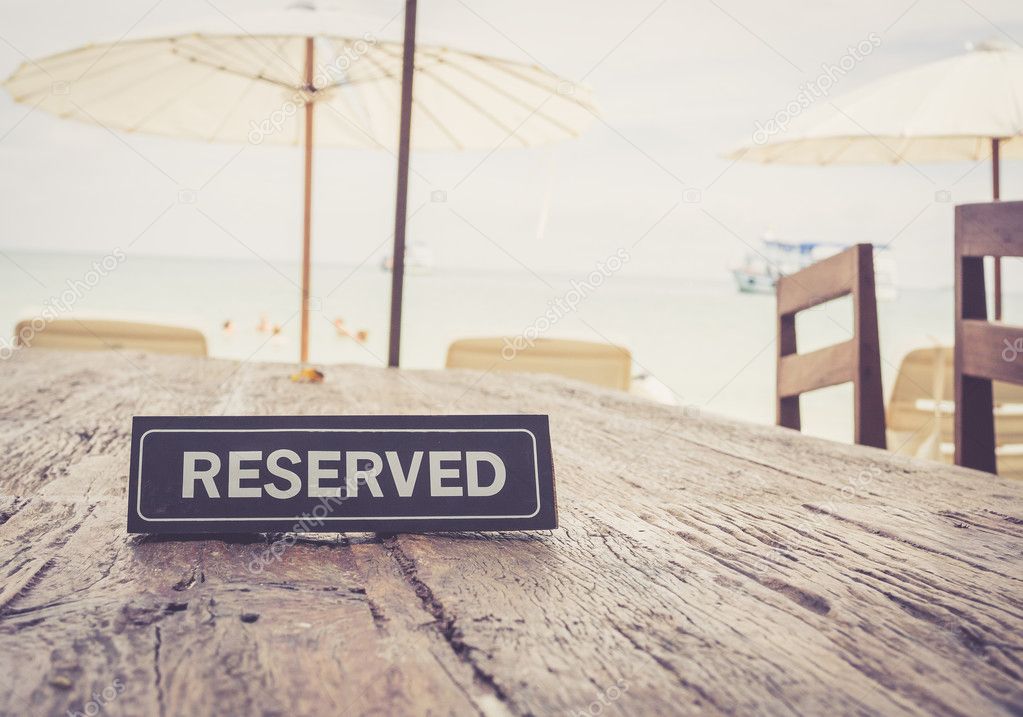 Reserved banner on restaurant table, beach background; vintage c
