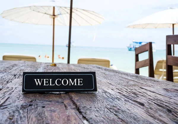 Banner de boas-vindas na mesa do restaurante, fundo da praia — Fotografia de Stock