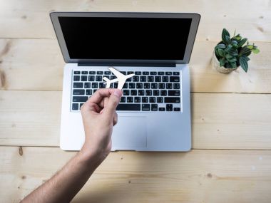 El ile ahşap masa üstünde bilgisayar defter ile tutarak hava uçak sembolü