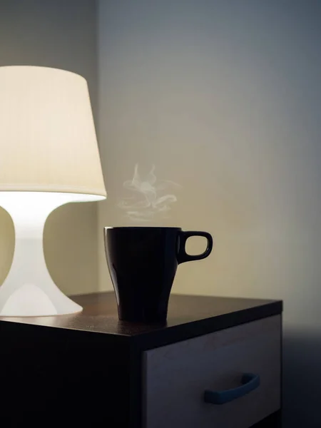 Tasse avec vapeur chaude et lampe sur le lit latéral — Photo