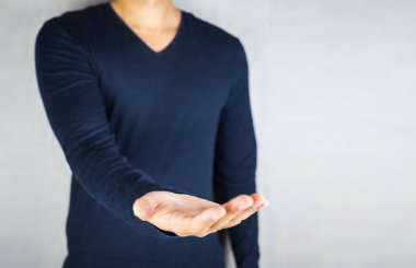 Adam açık elini, uzun kollu giyiyor, yüzü olmayan gri arka plan üzerinde