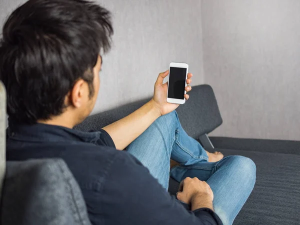 Man holding phone, sitting on sofa