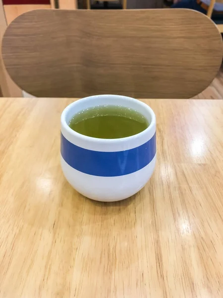 Hot green tea in teacup on table