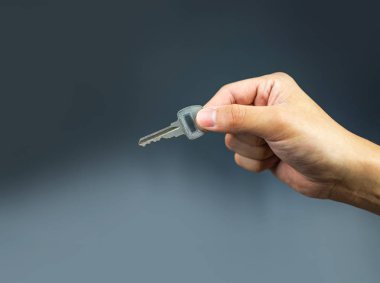 Koyu gri arka plan üzerinde tutan el üstünde anahtar