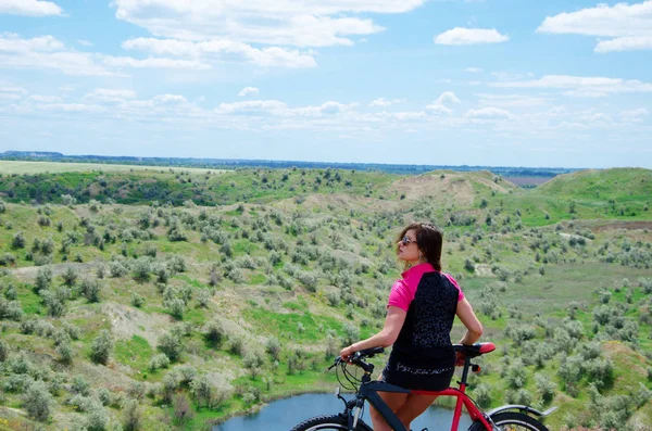 Flicka med en cykel på toppen av kullen — Stockfoto