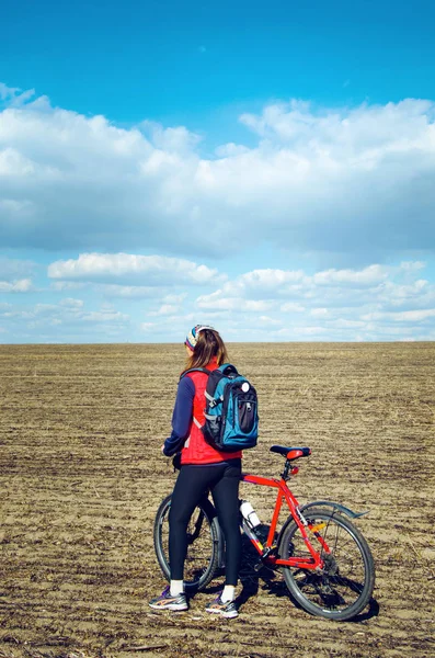 Flicka med en cykel i det öppna fältet — Stockfoto